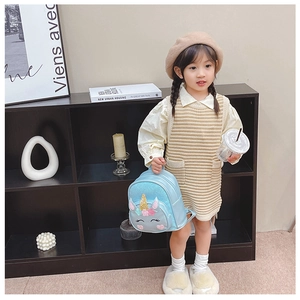 Toddler girl modeling a light blue sequin unicorn backpack in a modern home setting