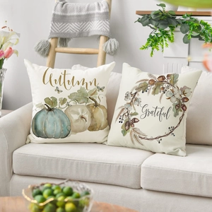 Set of autumn decorative linen pillow covers featuring pumpkins and Grateful text on a sofa