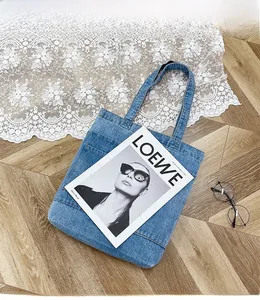 Dettaglio di una borsa tote in denim lavato blu su pavimento in legno con stile retrò