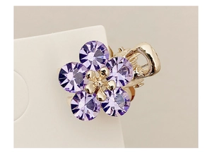 Detailed macro view of a mini floral hair claw with purple crystals and gold finish