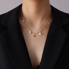 Primer plano de collar dorado elegante con perlas y dijes de estrella y luna en modelo