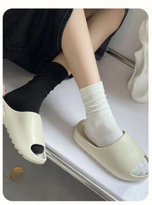 Detail of ribbed cotton mid-calf socks paired with stylish thick-sole slide sandals