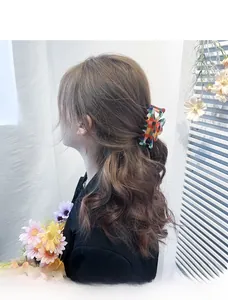 Detail of a large colorful checkerboard hair claw clip styled on long hair in a bun