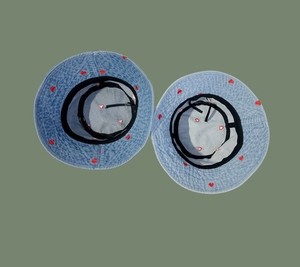 Detailed view of light blue denim bucket hats featuring red heart embroidery and inner straps