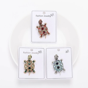 Detailed set of three rhinestone turtle brooches in red, green, and blue on display cards