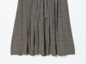Detailed macro shot of the pleated houndstooth fabric texture on a brown and white skirt