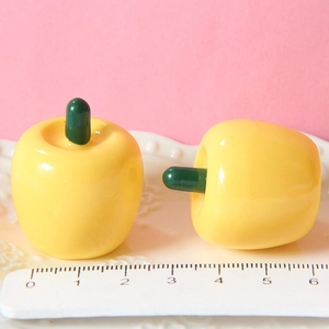 Macro shot of 2.5cm yellow resin apples on a white scale ruler for size reference
