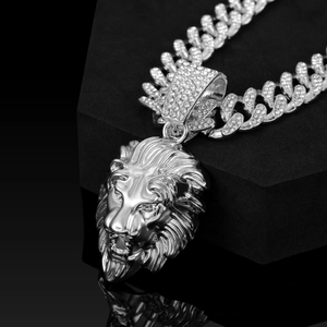 Detailed view of silver lion head pendant with gemstone Cuban link chain on black display