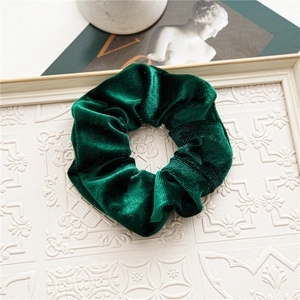 Close-up of deep green striped velvet scrunchie on a decorative white relief tray