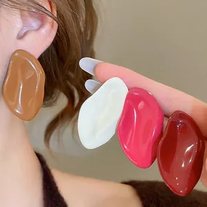Orecchini ovali irregolari minimalisti in vari colori indossati dalla modella