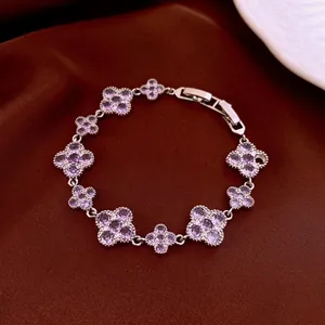Silver-tone bracelet with purple zircon four-leaf clover motifs on a dark satin backdrop