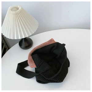 Detailed macro view of black knit tote bag with red and white striped contrast trim