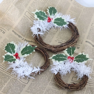 Détails de mini couronnes de Noël avec baies rouges et feuilles vertes enneigées
