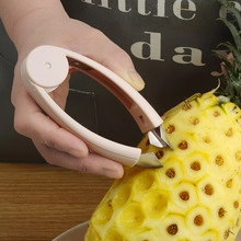 Close-up of pink pineapple eye peeler tool removing fruit seeds with metal jaw