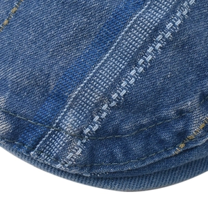 Detailed close-up of blue denim beret showing double-stitched seams and fabric texture
