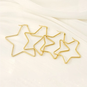 Set of four polished gold stainless steel star earrings in various sizes on white silk