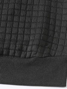 Close-up of black quilted sweatshirt featuring 3D lattice pattern and ribbed knit cuffs