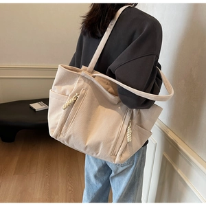 Detailansicht einer beigen Cord-Einkaufstasche mit Seitentaschen an einem weiblichen Model