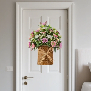Artificial floral hanging basket with olive daisies and pink flowers on a white door