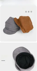 Detailed view of gray and brown suede newsboy caps with pleated design and soft lining