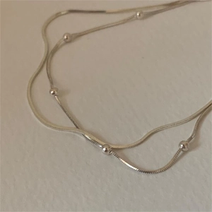 Detailed view of silver double-layered snake chain anklet with small metal beads