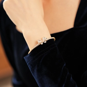 Détail d'un bracelet papillon doré avec ailes en zircone sur le poignet d'un mannequin