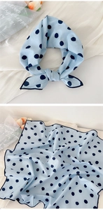 Detail of light blue polka dot scarf with navy binding and soft satin-like texture