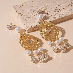 Elegant gold drop earrings with pearls and diamond tassels on a natural stone base