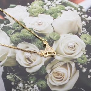 Elegant gold cocktail glass pendant necklace with zircons on a white rose background