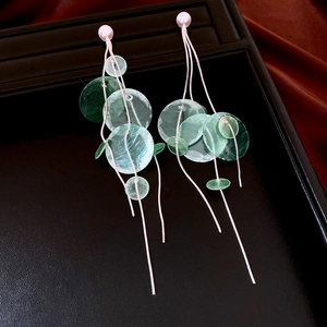 Detail of green shell drop earrings with elegant pearl studs and silver metal chains