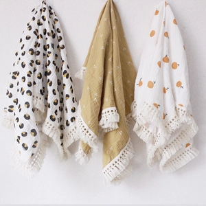 Three-pack cotton gauze baby swaddle blankets with tassels in leopard, floral, and orange prints