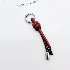 Detailed view of a brown braided leather keychain with silver metal rings and ends