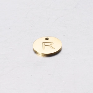 Macro shot of 12mm gold stainless steel round charm with letter R engraving for DIY jewelry