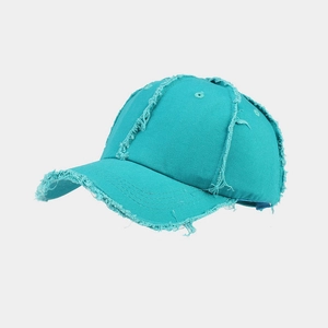 Detail of turquoise distressed baseball cap featuring frayed edges and vintage cotton canvas