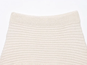 Detail view of cream white knitted mini skirt waistband with textured fringe fabric