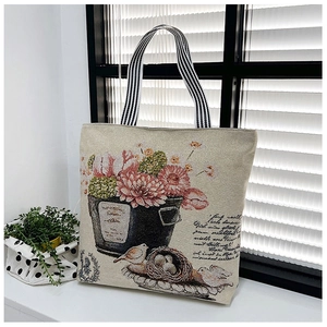 Detail of floral and bird nest embroidery on canvas tote bag with striped handles