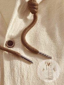 Gros plan détaillé du sweat à capuche en lin beige montrant la texture et les cordons tressés