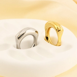 Macro view of polished 18k gold and silver irregular square rings on a display tray