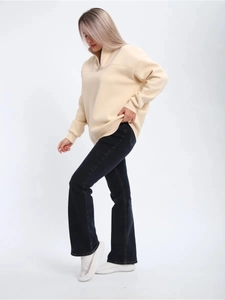 Detail of cream half-zip sweatshirt and flared jeans on model for casual autumn style