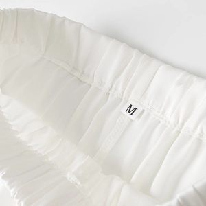 Détail de la taille élastique et de l'étiquette taille M sur le pantalon en satin blanc