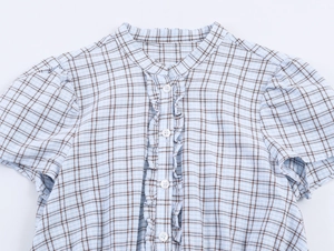 Detail of plaid shirt dress with ruffled trim and white buttons on blue cotton fabric