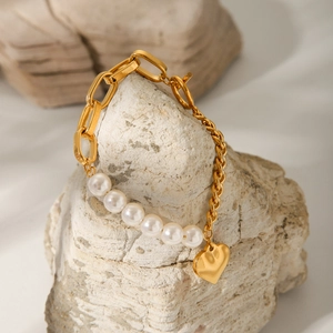 Detailed shot of gold heart pendant and white pearls on mixed stainless steel chain