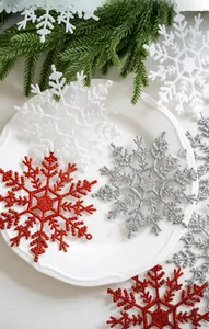 Dettaglio di fiocchi di neve natalizi glitterati in plastica rossa, argento e bianca
