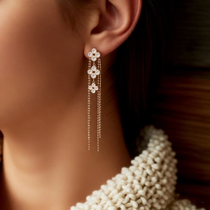 Detail of 18K gold-plated floral fringe earrings with tassel chains on a model