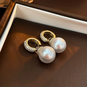 Macro detail of gold plated pearl earrings with zircon inlay on a luxury jewelry box