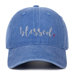 Detailaufnahme der 'blessed' Stickerei und des roten Kreuzes auf blauer Baumwollkappe