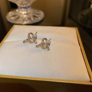 Macro shot of gold knot stud earrings with micro-inlaid cubic zirconia crystals