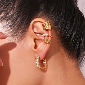 Detail of 4-piece gold ear cuff set with rhinestones and pearls on model ear