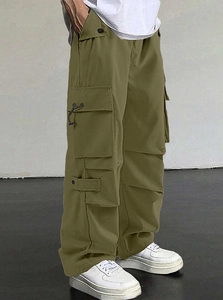 Detail of olive green parachute pants featuring functional side cargo pockets and drawstrings