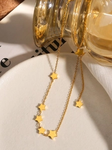 Detailed close-up of a gold-plated star necklace on a minimalist ceramic display